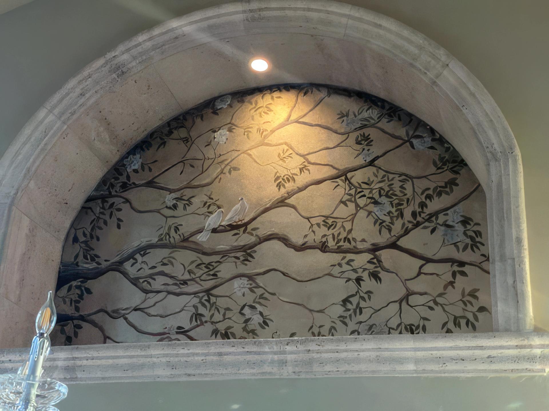 Hand-painted chinoiserie mural in arched stone niche with bird and branch motif, residential interior, neutral tones