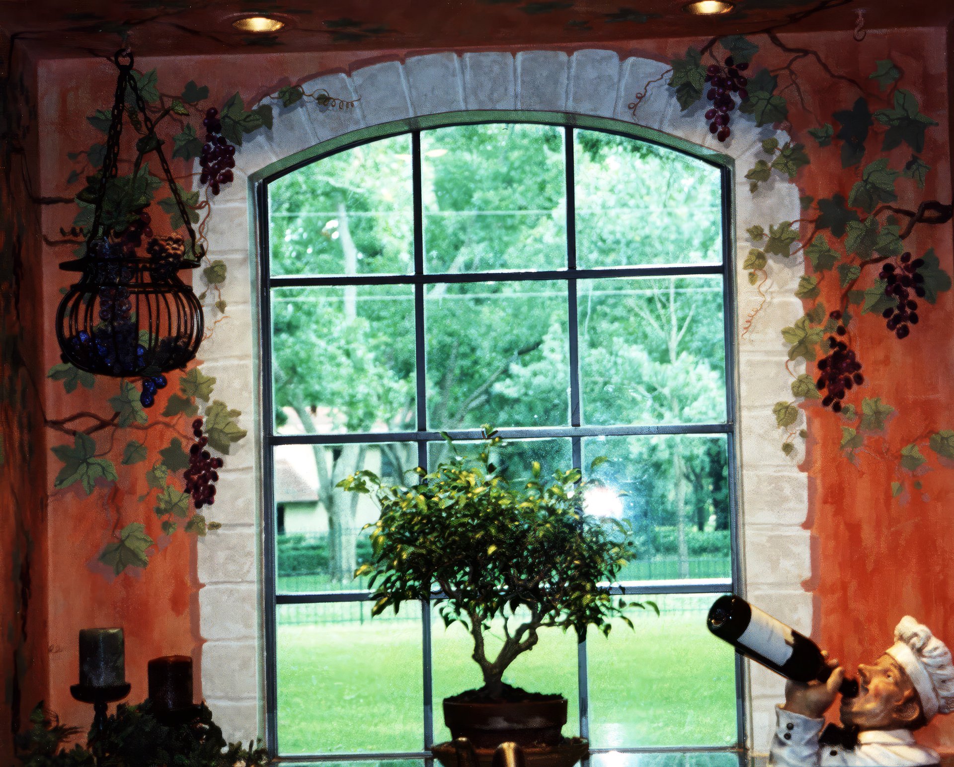 Tuscan faux fresco kitchen walls with hand-painted trompe l'oeil grapevine mural framing arched window, Houston.