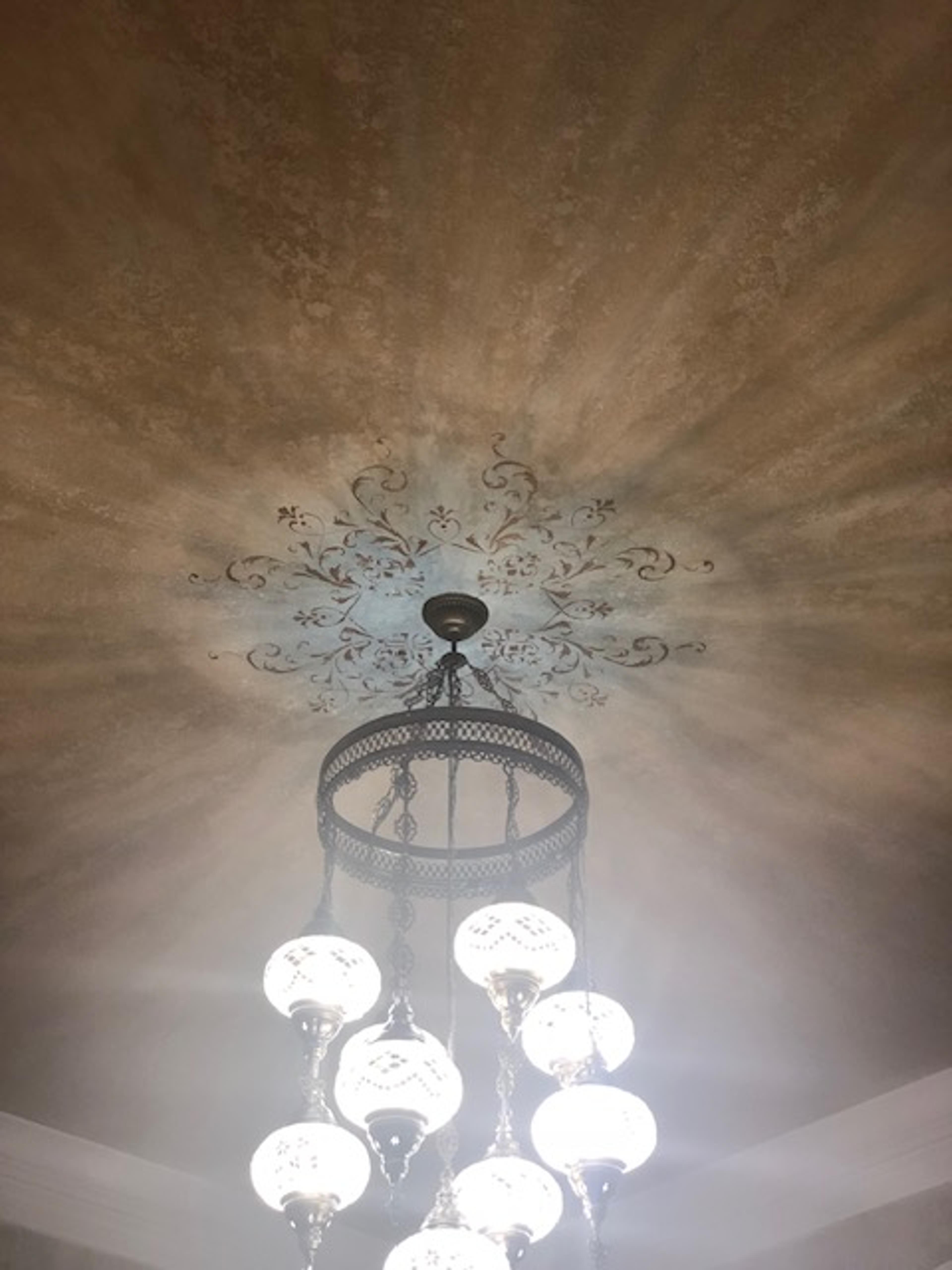 Venetian plaster ceiling with radial burnished glaze and hand-painted scroll medallion surrounding chandelier, dining room