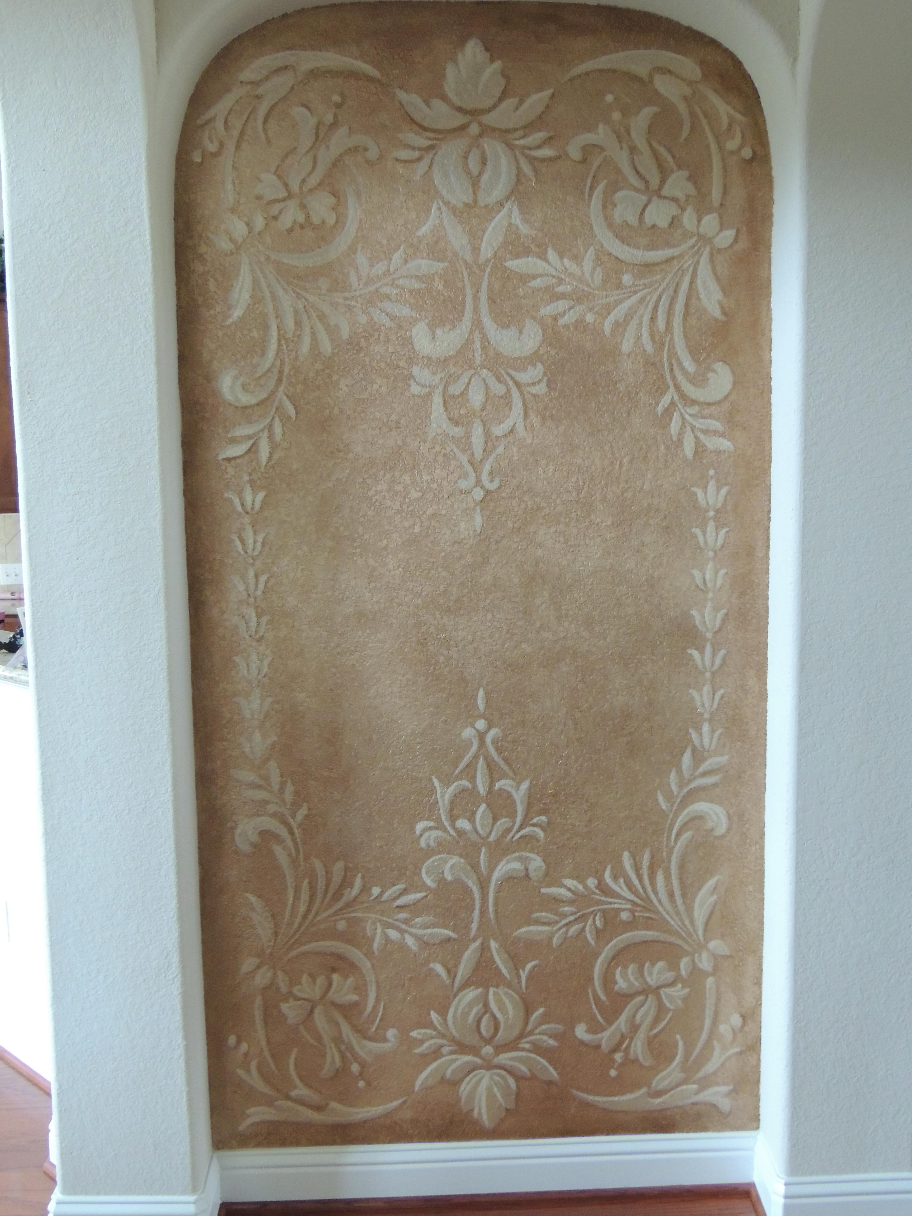 Venetian plaster arched niche with tone-on-tone damask stencil in warm amber and cream, residential foyer.