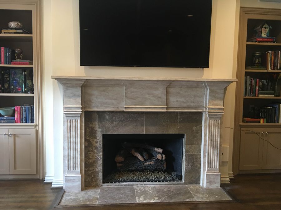 Faux aged limestone finish on fireplace mantel and pilasters in family room with built-in bookshelves, Houston.