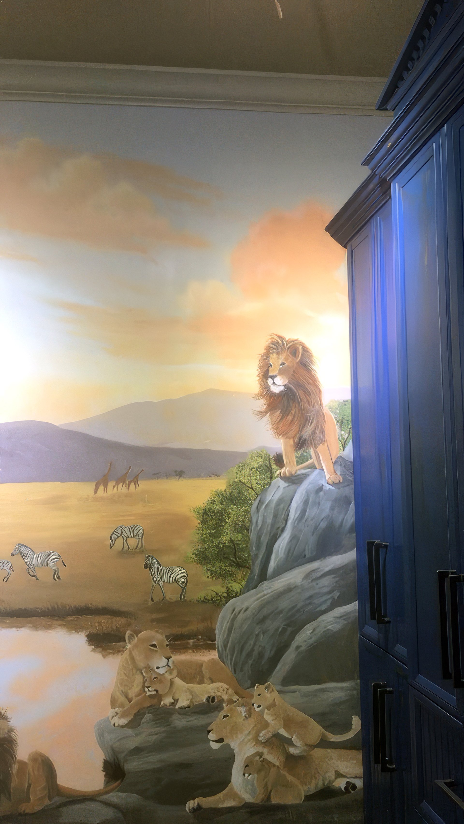 Hand-painted African savanna mural in children's bedroom with lion pride, zebras, and layered landscape depth.