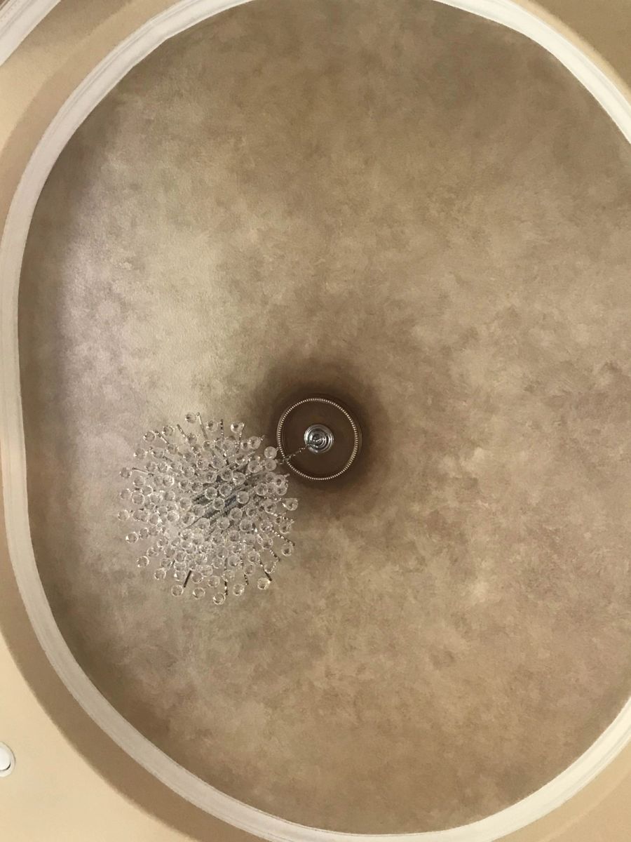 Venetian plaster dome ceiling in warm gold and taupe with mottled finish, crystal chandelier, and white crown molding ring.