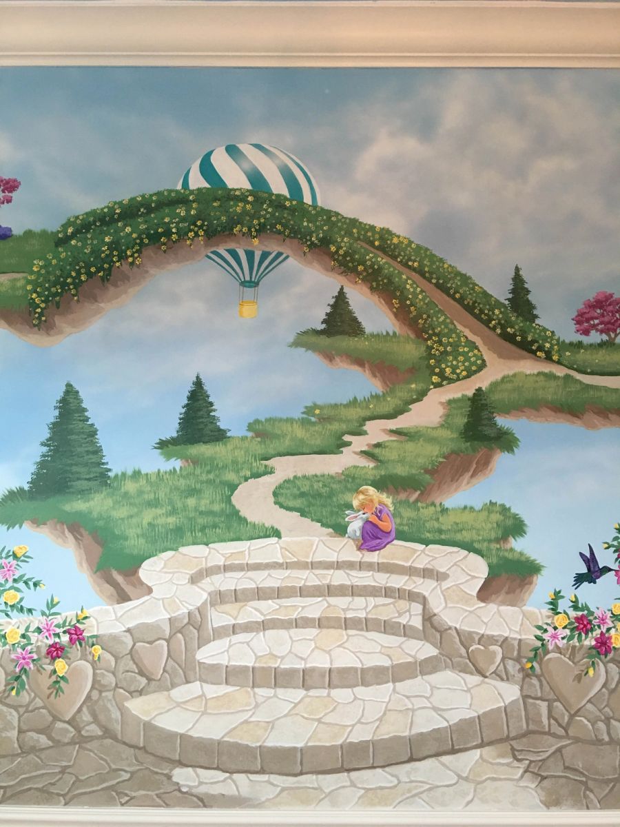 Hand-painted children's fantasy mural with floating islands, stone arch bridge, hot air balloon, and girl with bunny on trompe l'oeil steps.