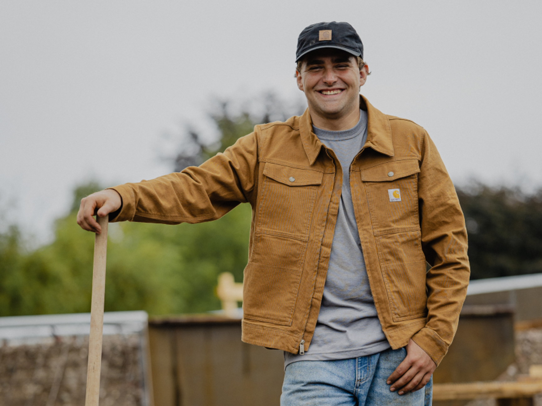en man iklädd carharttjacka och keps som ler