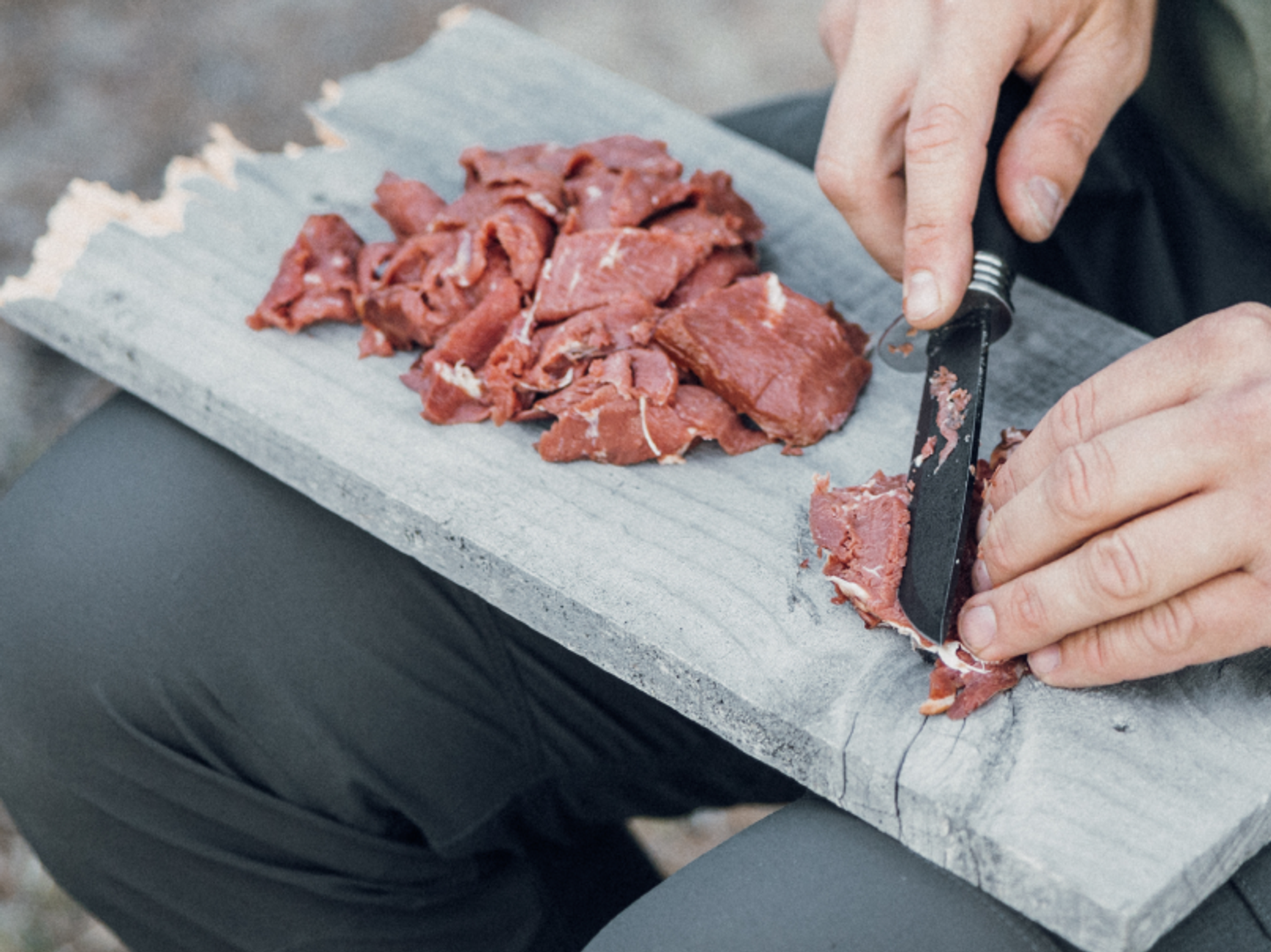 en kniv som skär tunna skivor kött på en skärbräda