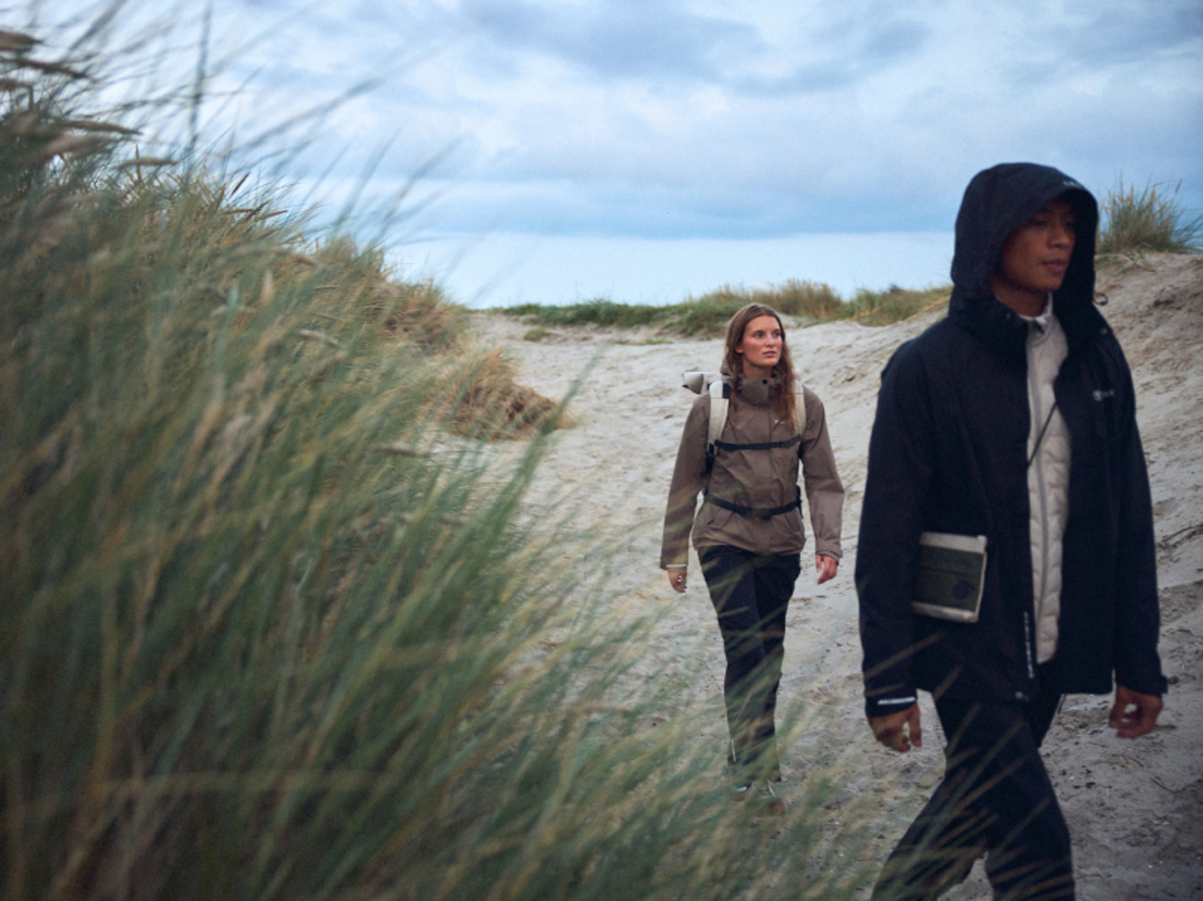 två personer med friluftskläder på en strand