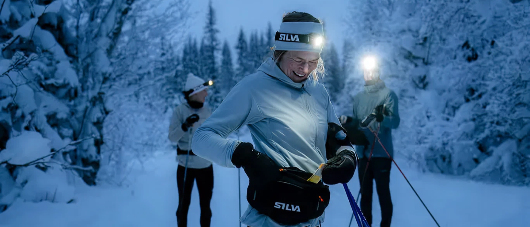 kvinna som åker längdskidor med pannlampa påslagen