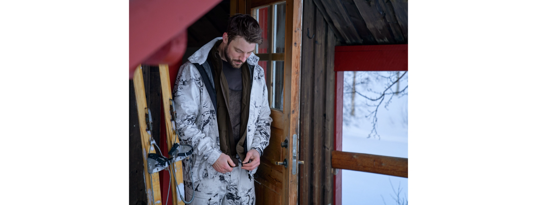 man i snöcamo vid en jaktstuga