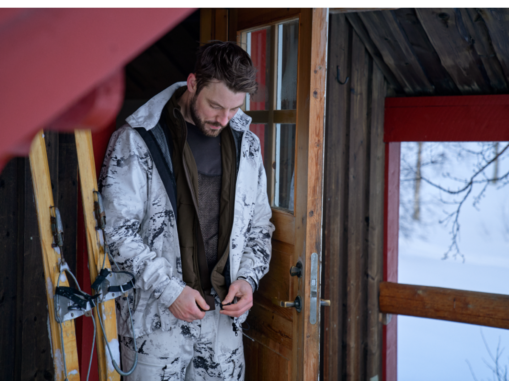 man i snöcamo vid en jaktstuga