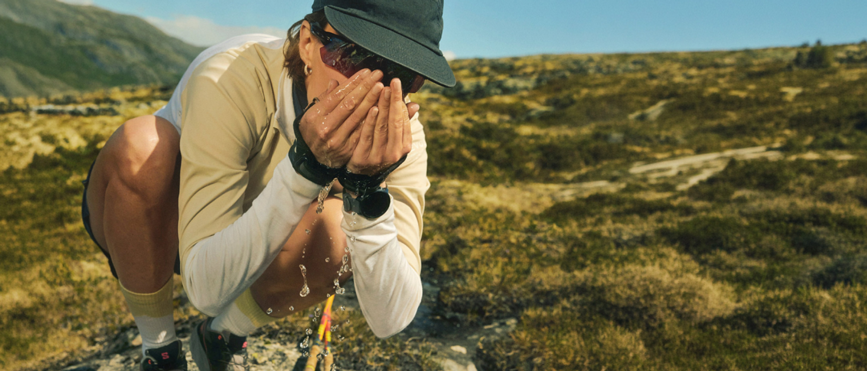 person som dricker ur en fjällbäck