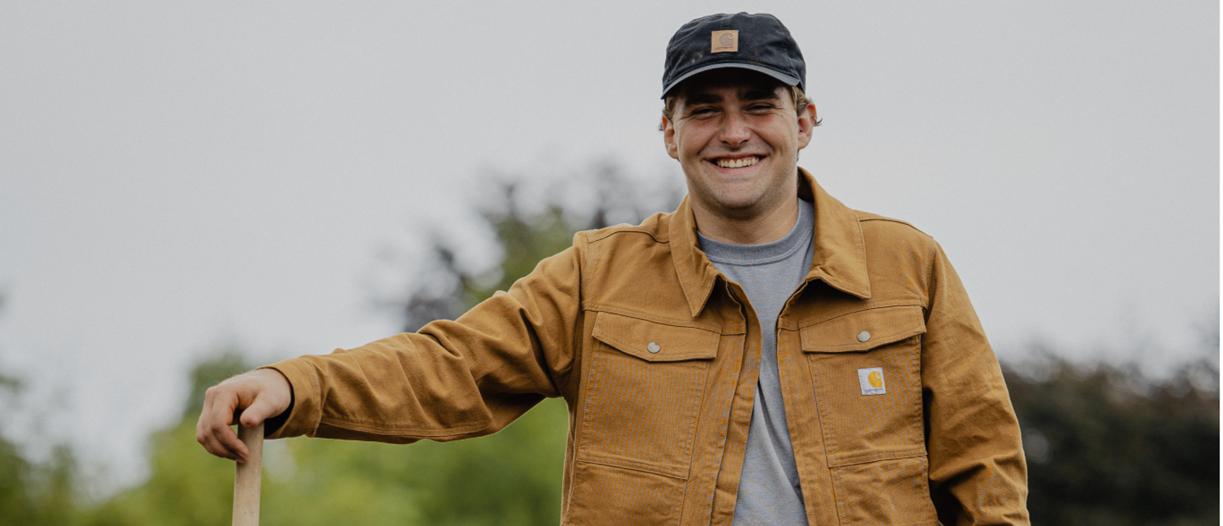 en man iklädd carharttjacka och keps som ler