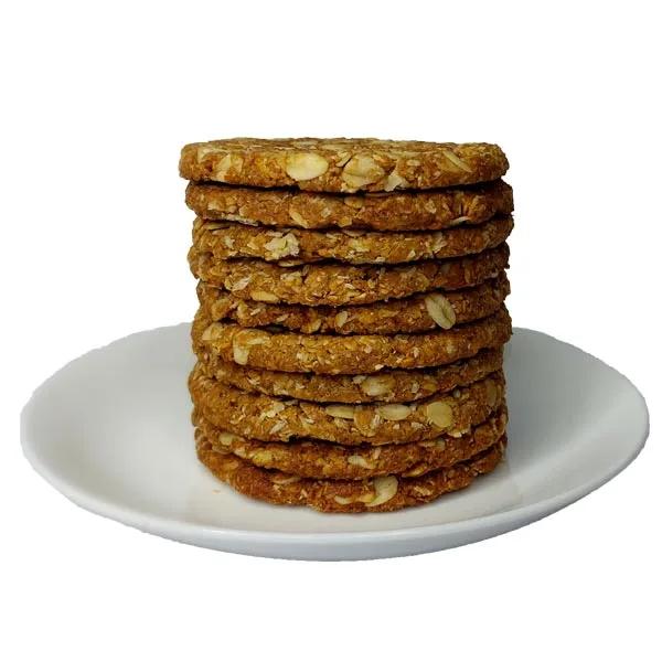 A stack of golden Anzac biscuits on a wooden board