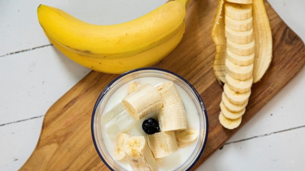 Et glass med banansmoothie, pyntet med blåbær og biter av banan.