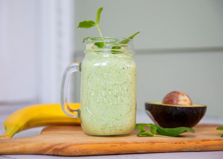 Avokado- og banansmoothie servert i glass, toppet med friske mynteblader.