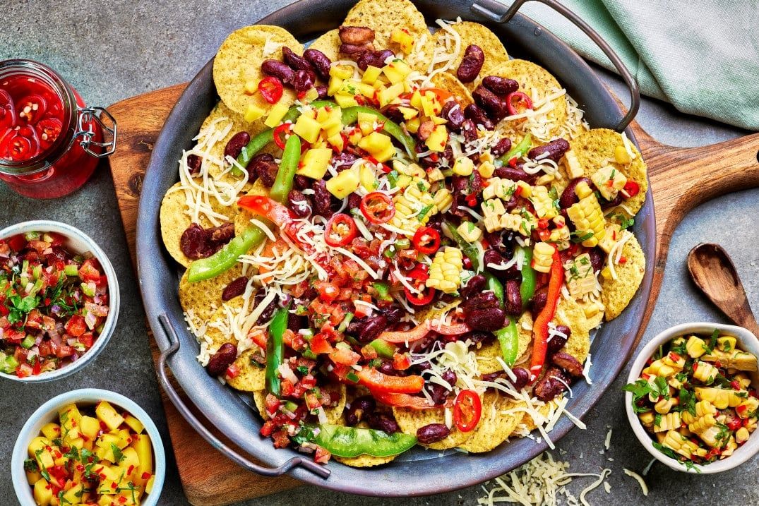 Stor panne med nachos toppet med tortillachips, revet ost, røde bønner, mais, paprika, sukkererter og skiver av chili. 