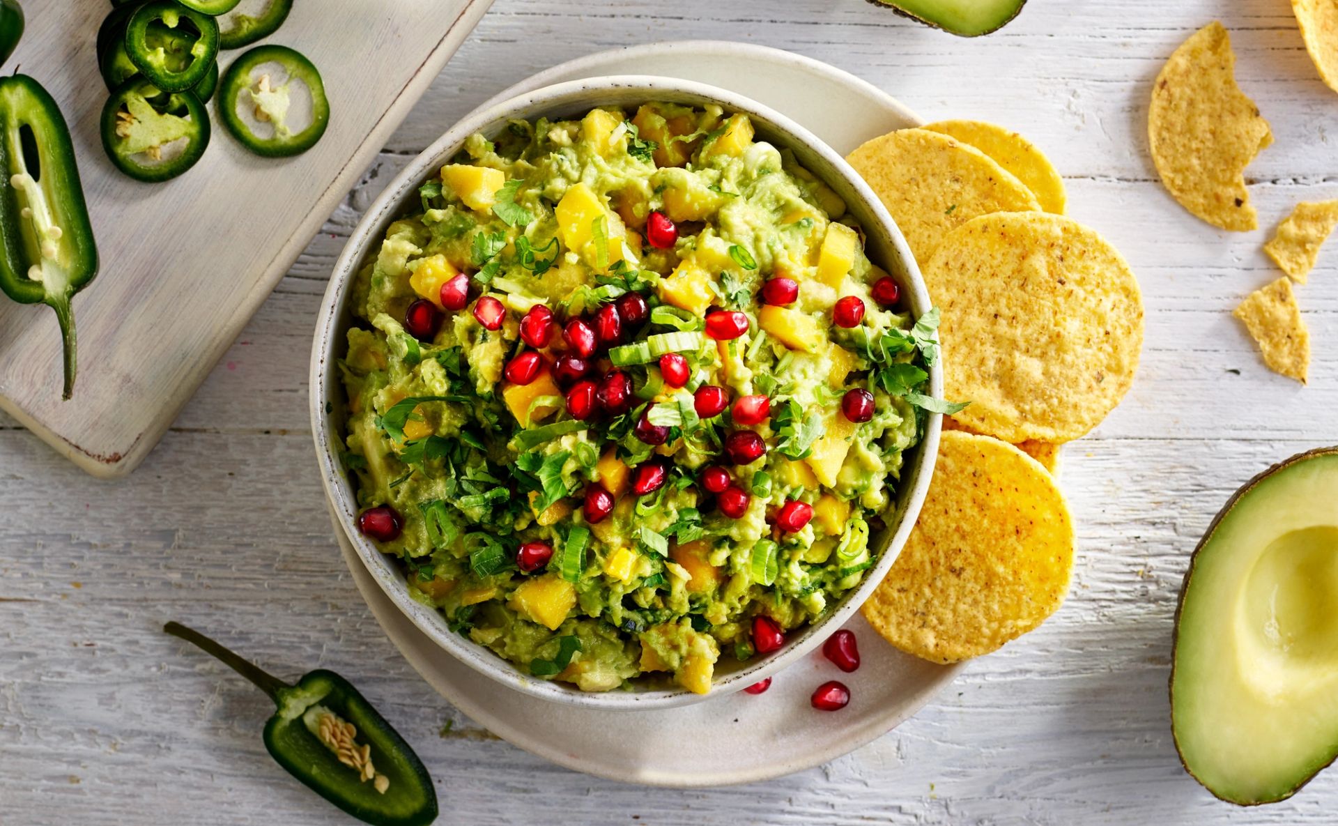 En bolle med frisk mango-guacamole toppet med røde granateplekjerner og fersk koriander.