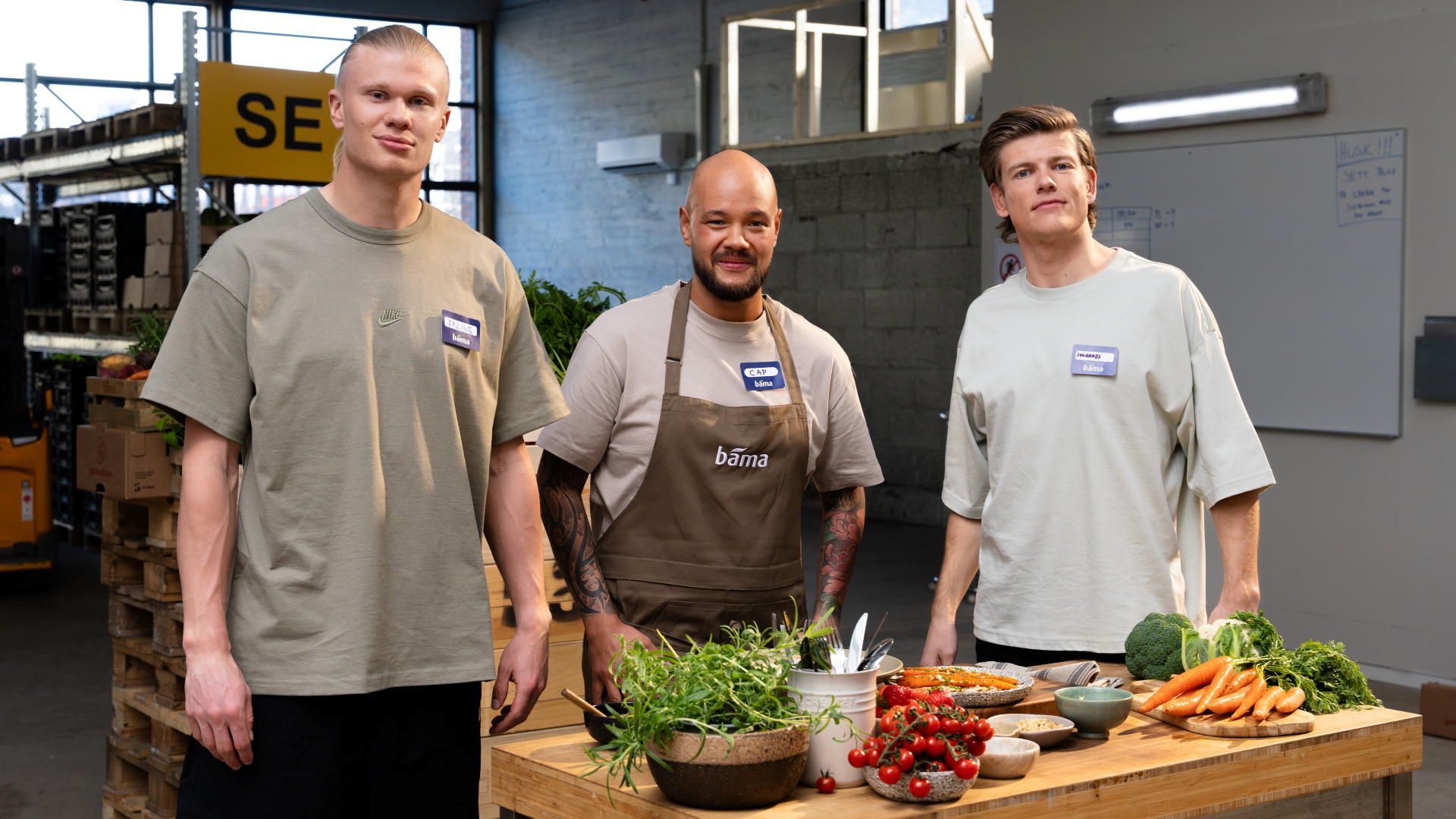 Bilde av Johannes Klæbo, Erling Haaland og Christian Andre Pettersen bak et bord med grønnsaker. 