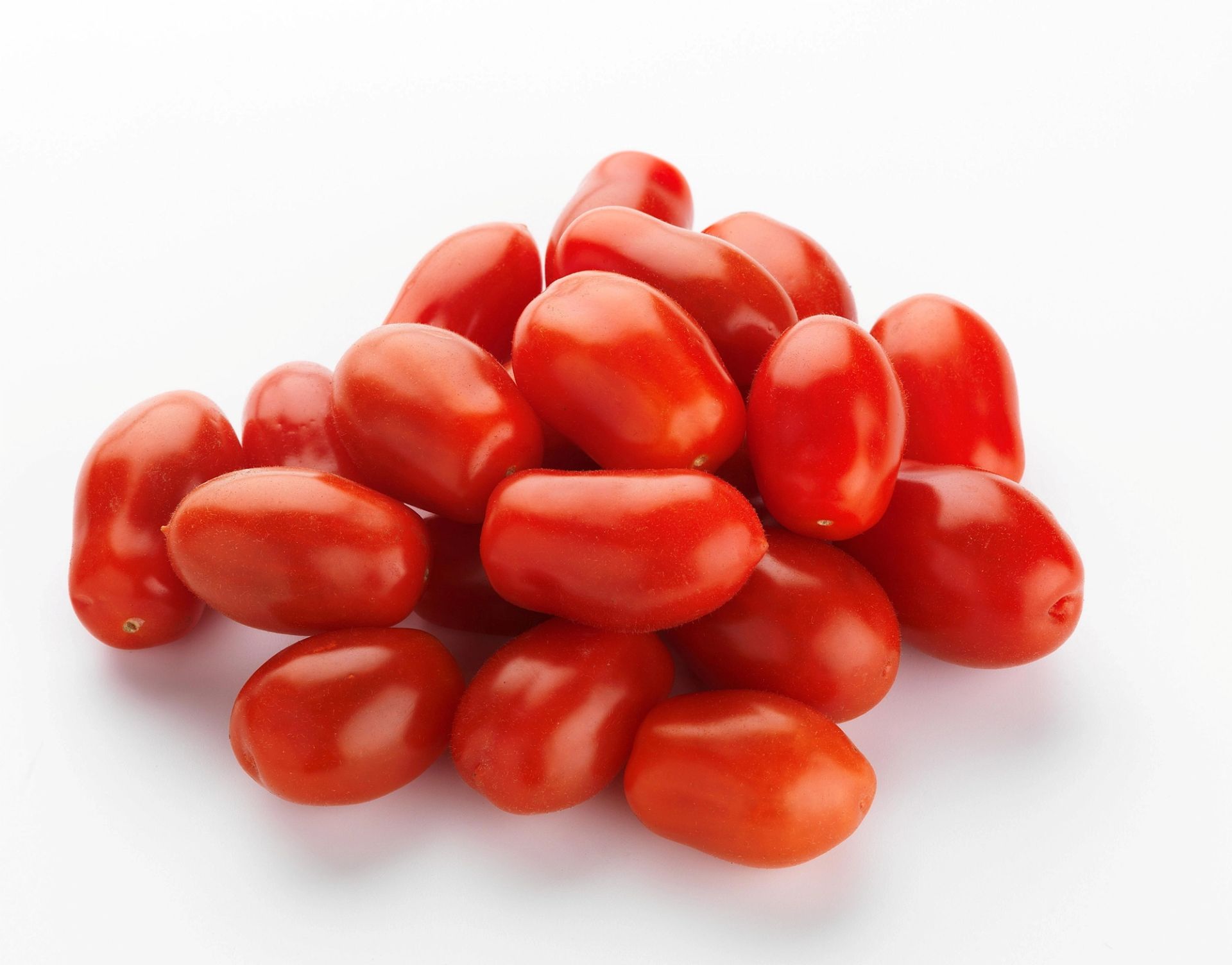 En liten haug med røde, ovale cherrytomater (plommetomater) plassert på en hvit bakgrunn