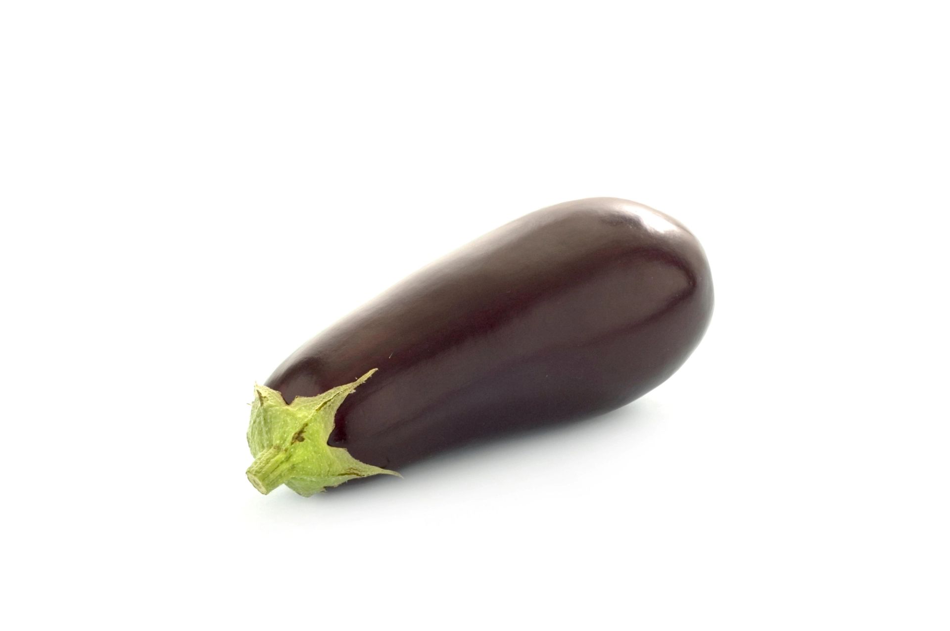 En hel aubergine med blankt, mørkelilla skall og en lysegrønn stilk, liggende på en hvit bakgrunn.