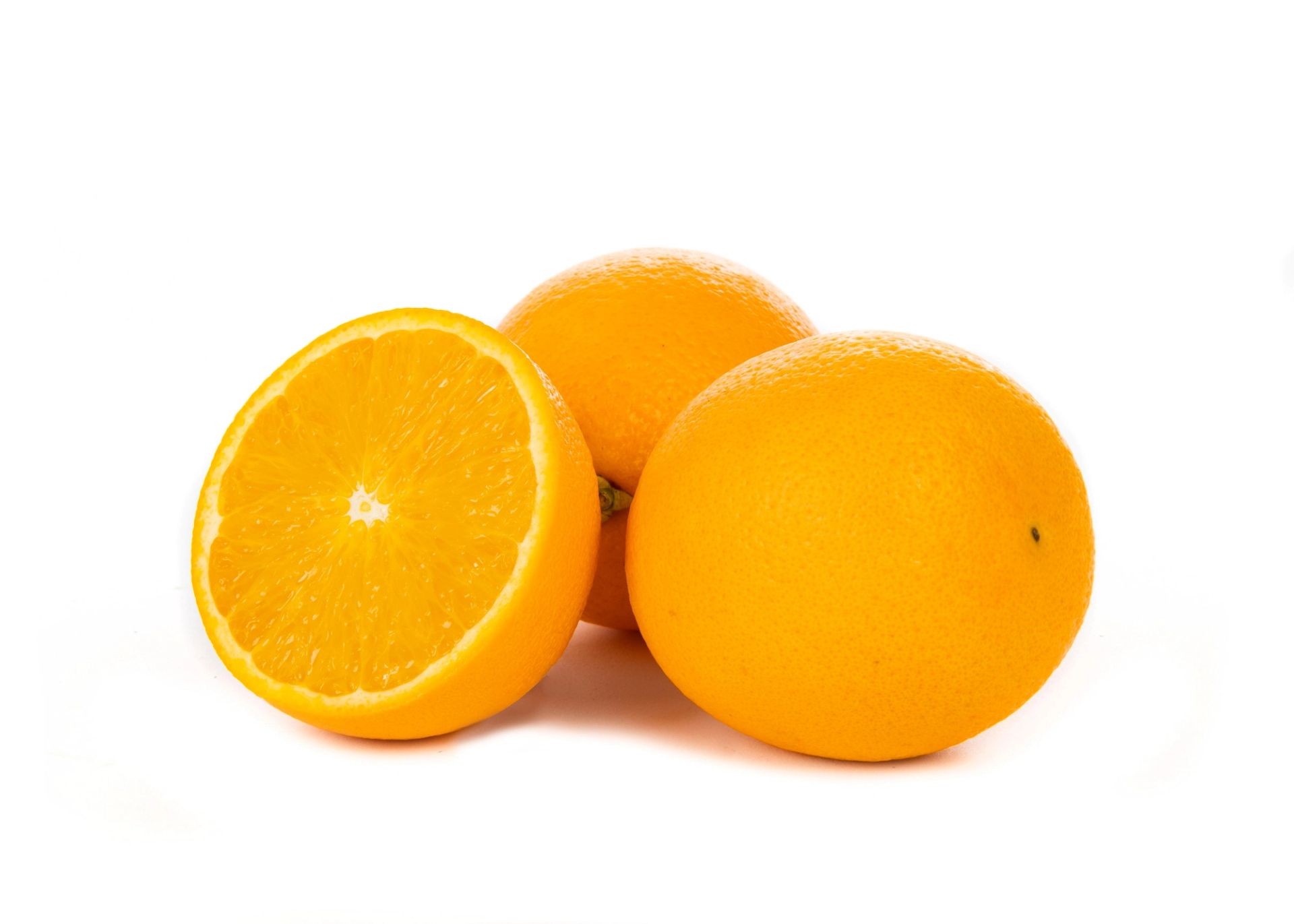 To hele appelsiner og en halvert appelsin med saftig, oransje fruktkjøtt plassert mot en hvit bakgrunn.