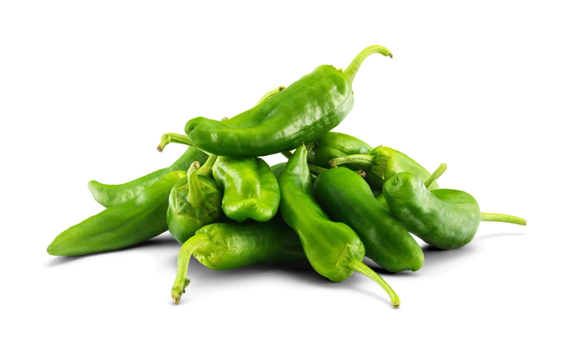 En haug med friske grønne padron‑paprika liggende på hvit bakgrunn.