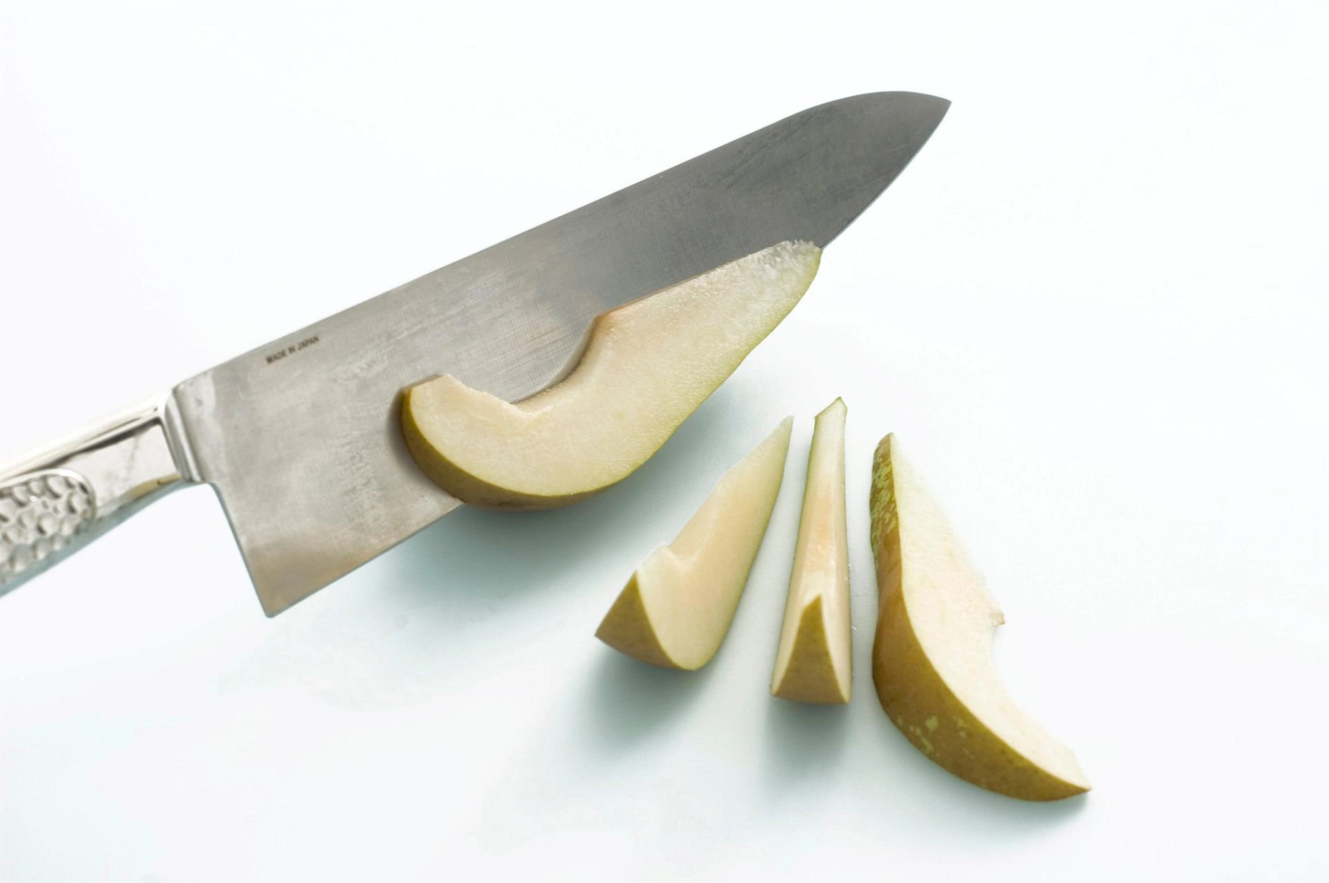 Pærebåter som skjæres med kniv på hvit bakgrunn.