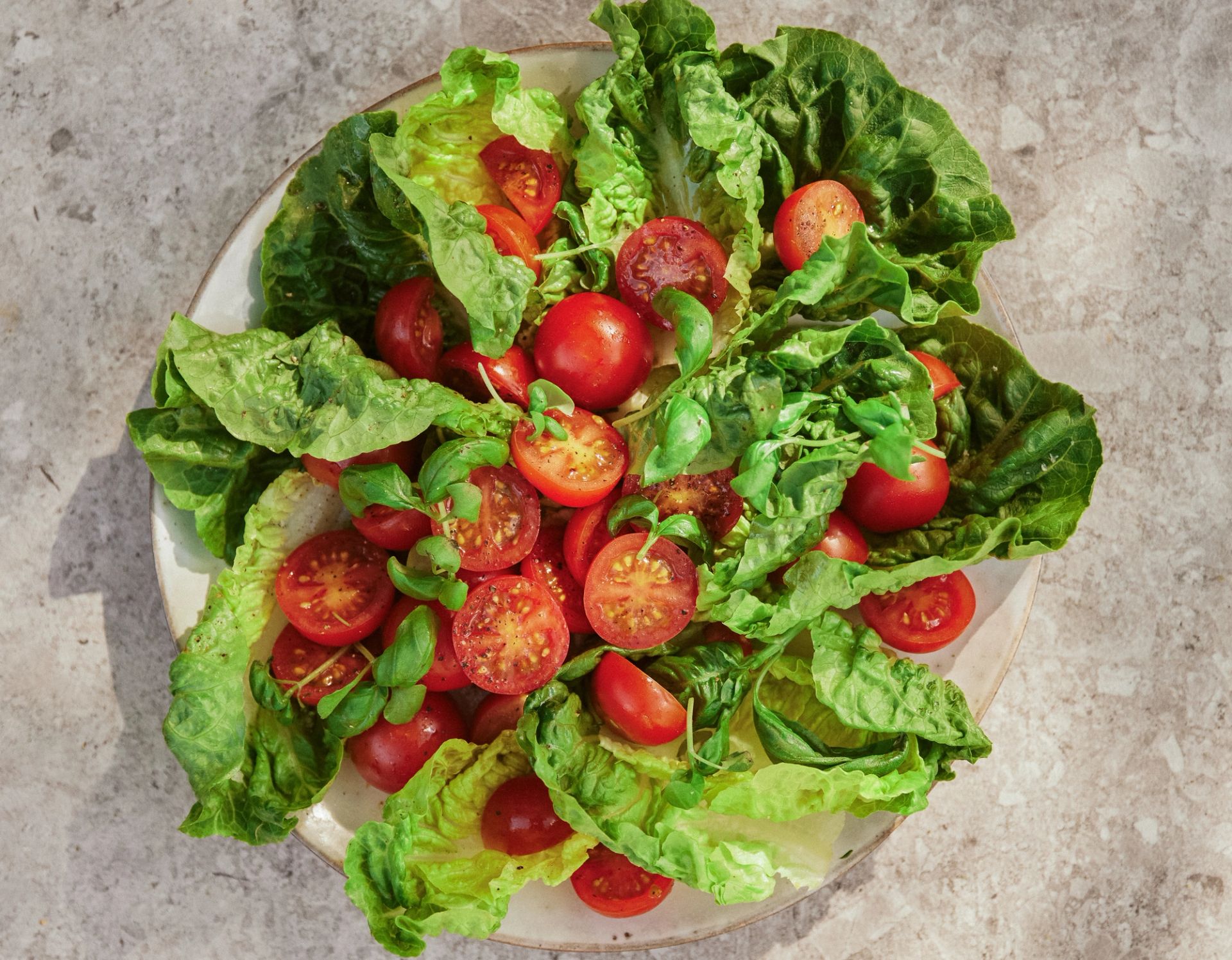 Hjertesalat med cherrytomatet på et fat, toppet med basilikum.