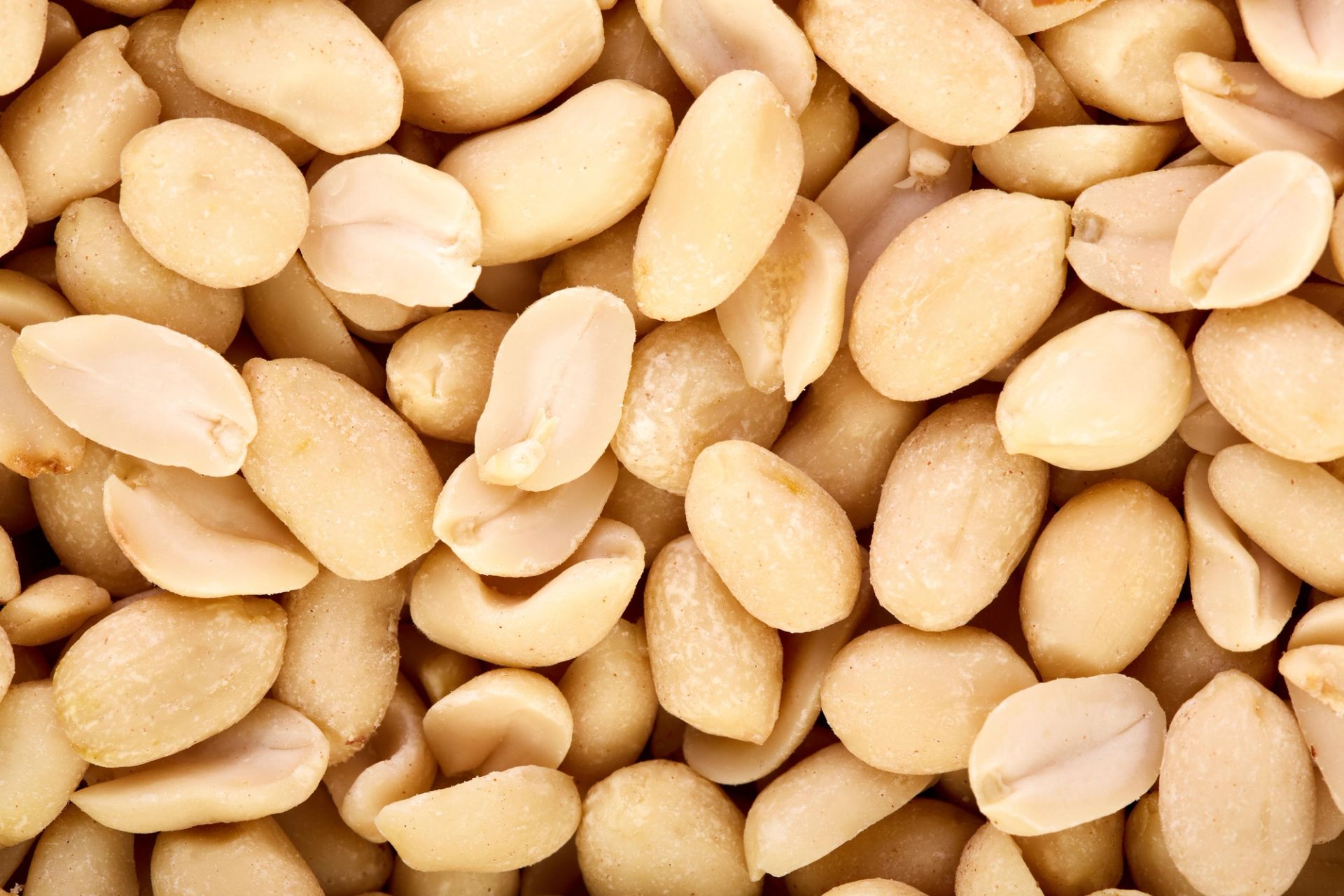 Nærbilde av skrellede, delte peanøtter med lys, beige overflate.