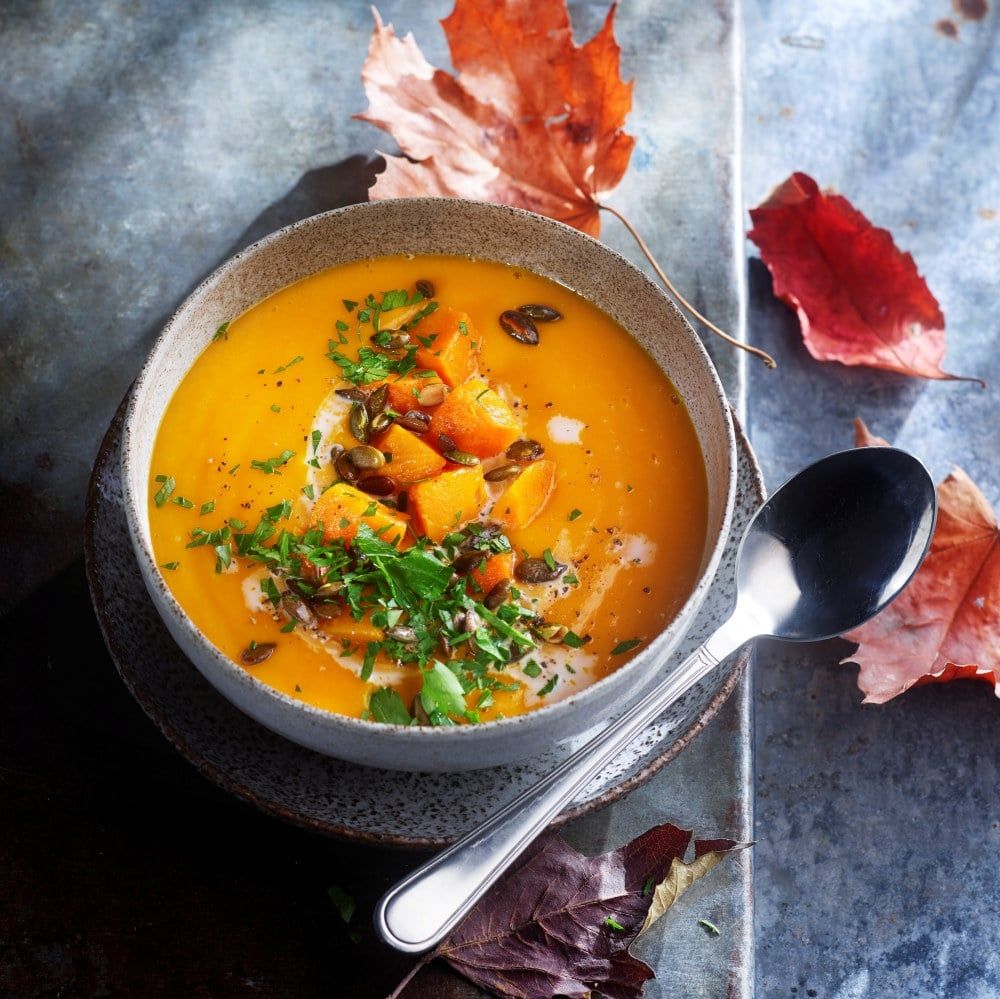 Enkel gresskarsuppe servert i skål, toppet med gresskarkjerner, urter og biter av bakt gresskar.