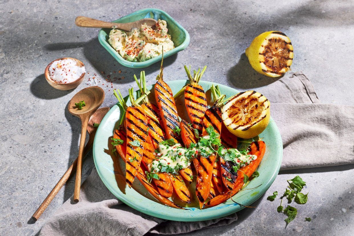 Grillede gulrøtter med kryddersmør og grillede sitroner servert på tallerken