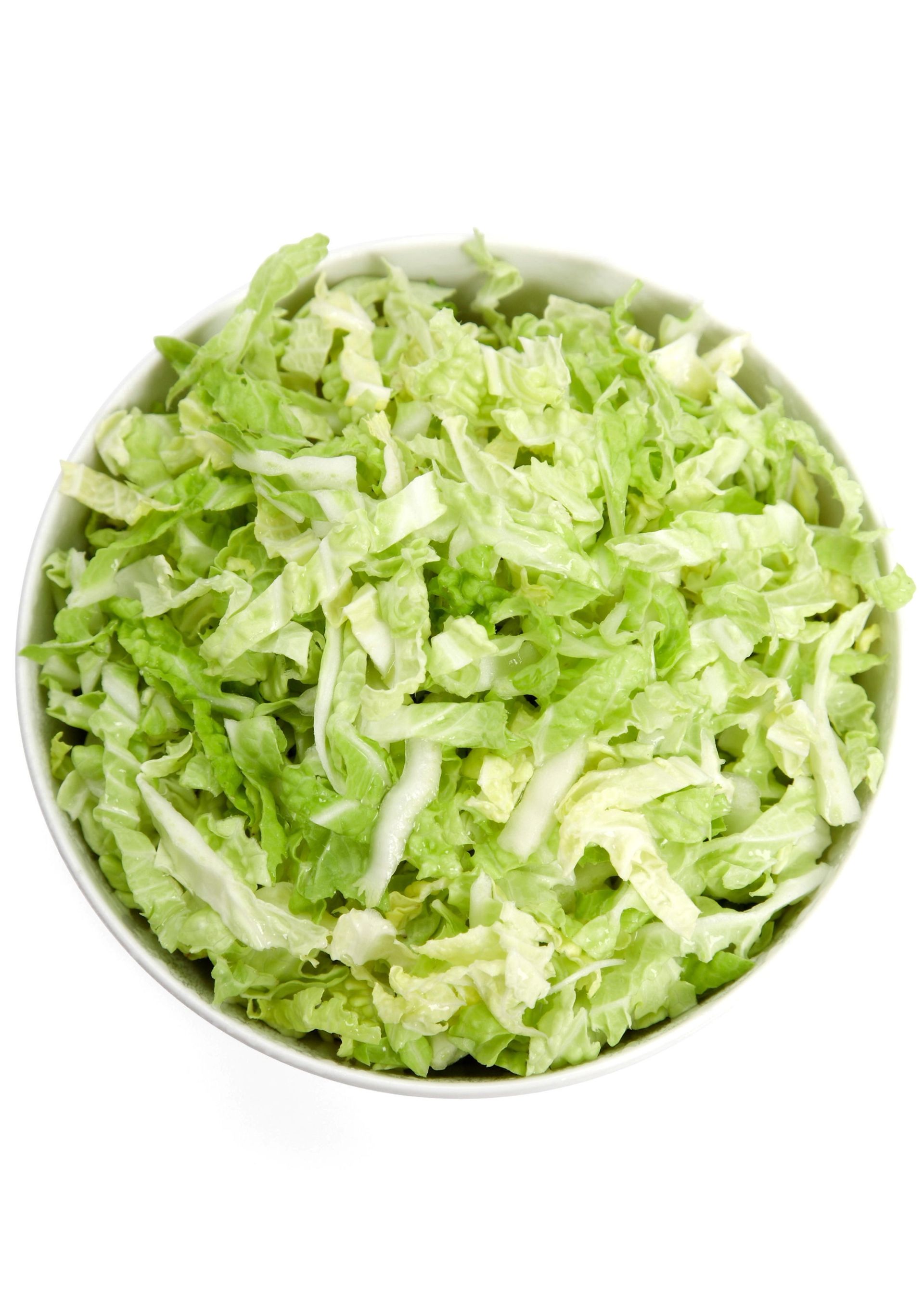 Skål fylt med finstrimlet isbergsalat på hvit bakgrunn.