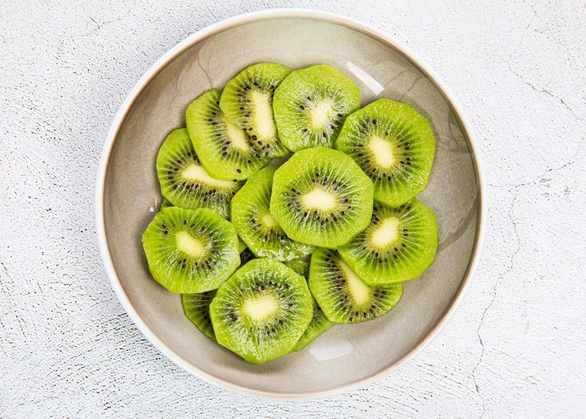 En bolle sett ovenfra, fylt med tynne skiver av grønn kiwi lagt i et sirkelformet mønster