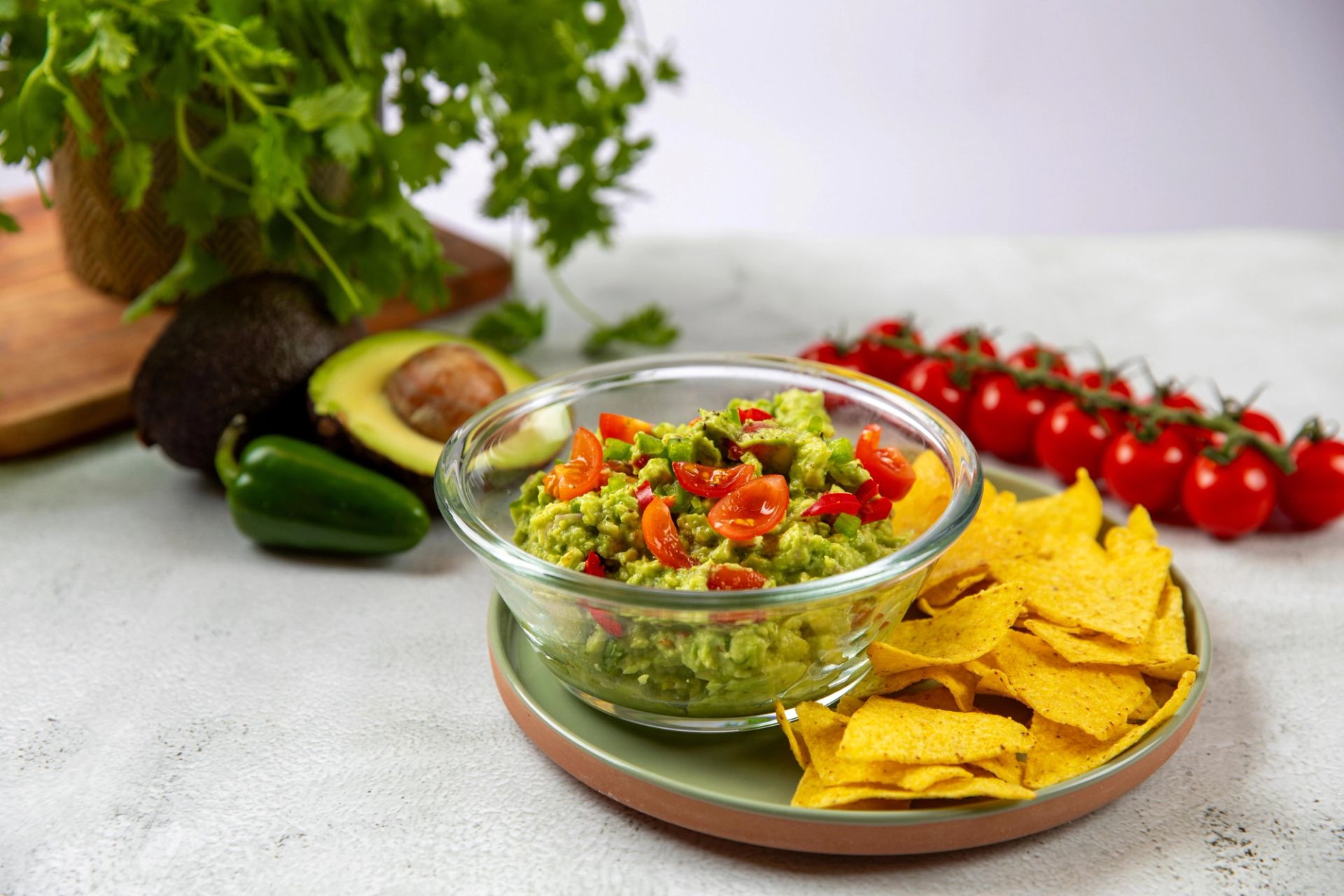 Guacamole toppet med cherrytomater, servert med tortillachips, avokado og friske tomater.