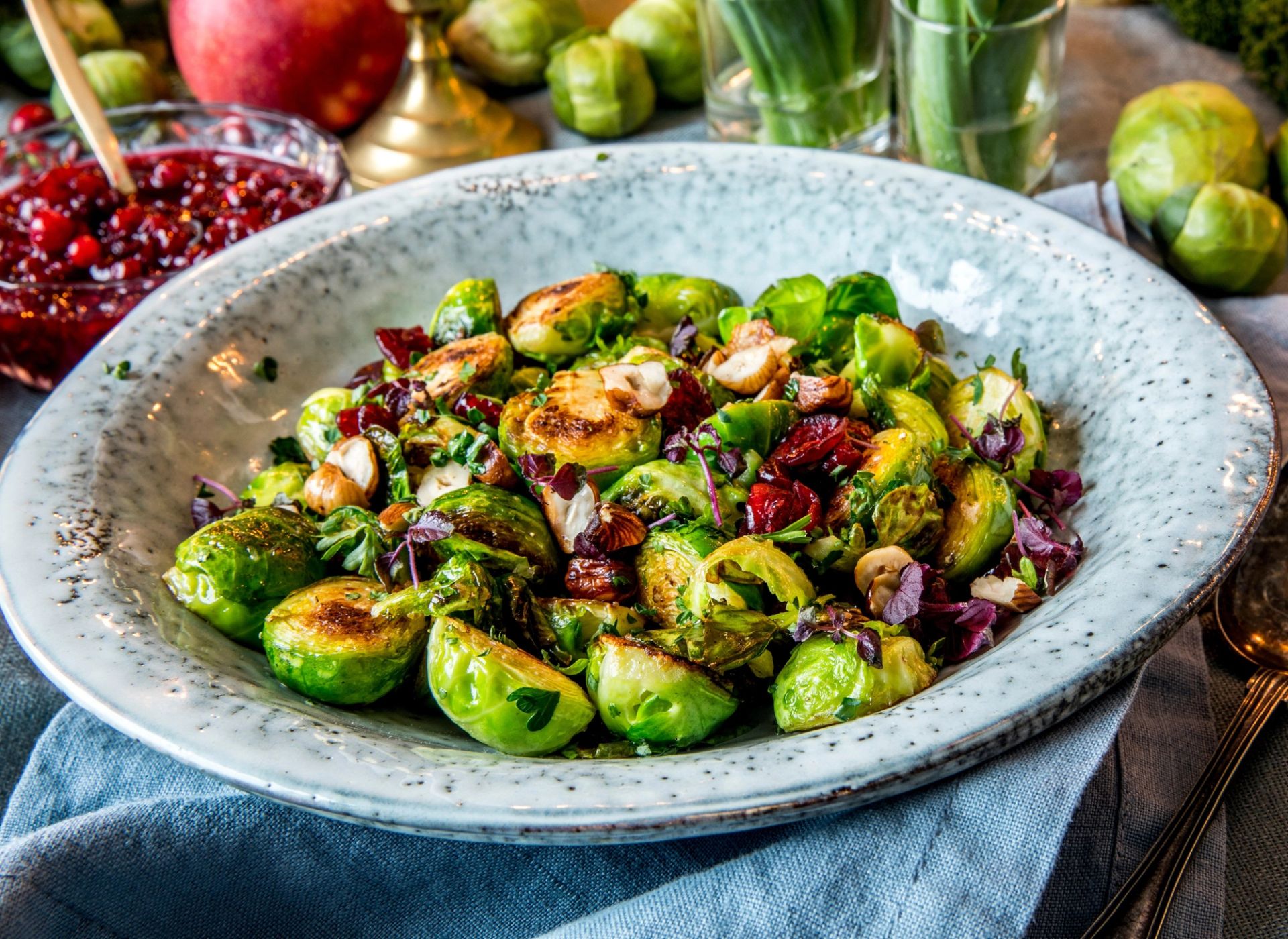 Gyldenstekt rosenkål med nøtter, tørkede tranebær og bladpersille på fat – perfekt til middag