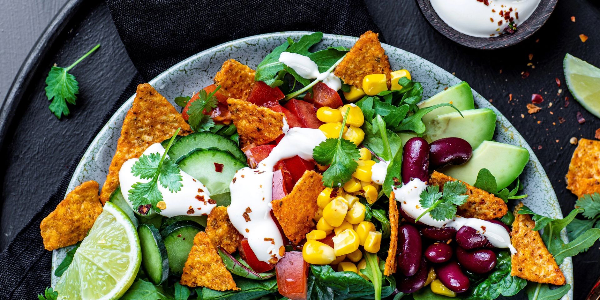 Enkel tacosalat med kidneybønner, mais, avokado, agurk, tomater og rømmedressing servert i bolle sammen med tortillachips.