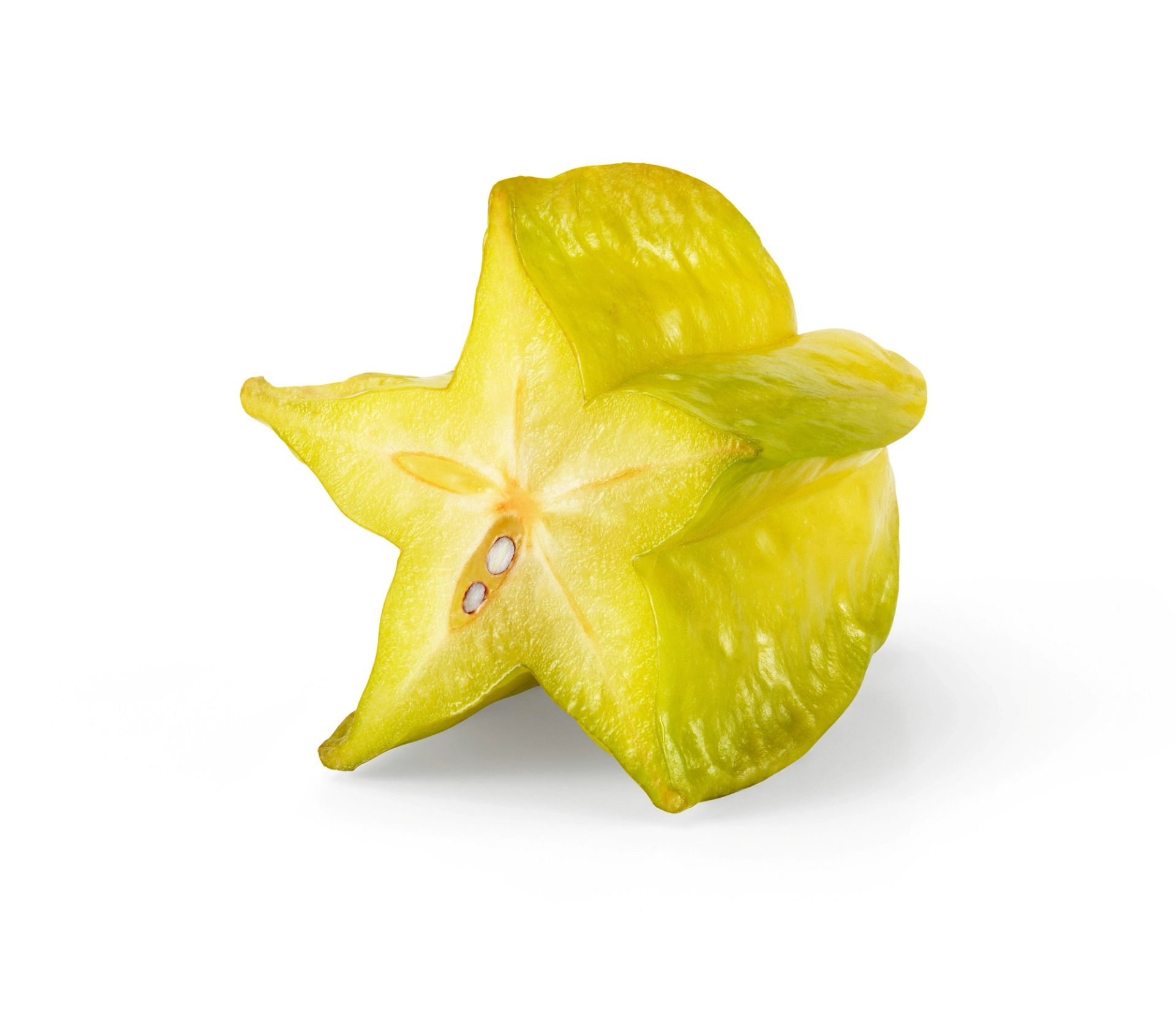 En gulgrønn stjernefrukt (carambola) lagt på siden, der den karakteristiske stjerneformen er tydelig synlig i snittet.