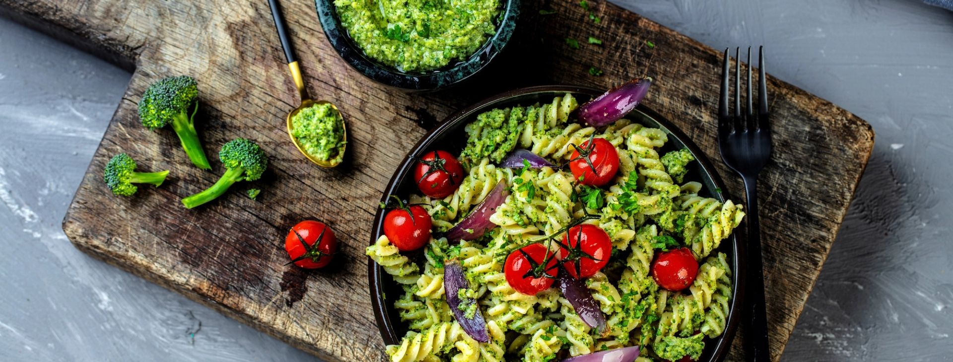 Fusilli med brokkolipesto og cherrytomater servert i bolle på rustikk trefjøl