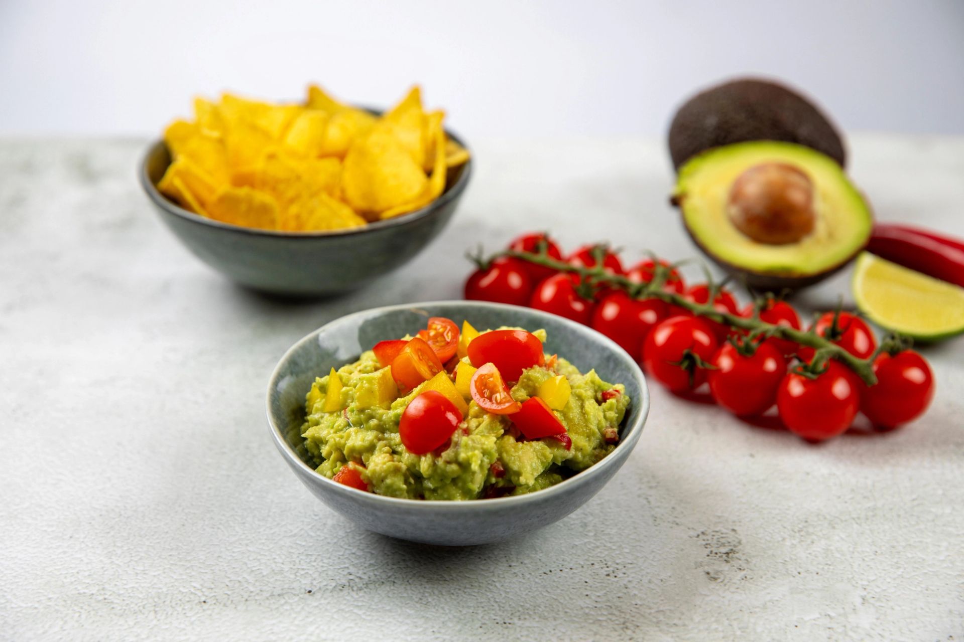 Guacamole toppet med cherrytomater og mango, servert med chips.