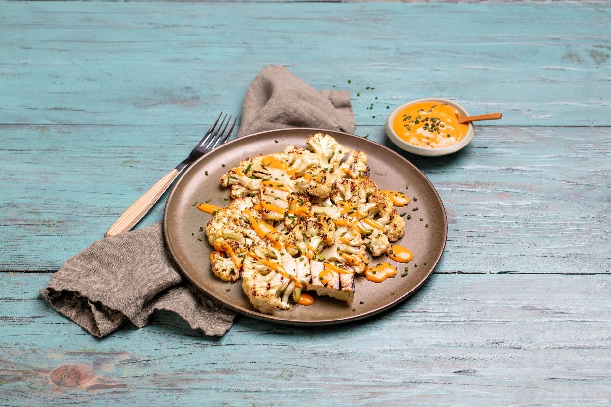 Grillede blomkålbiffer servert med yoghurt- og chilidipp på rustikt bord