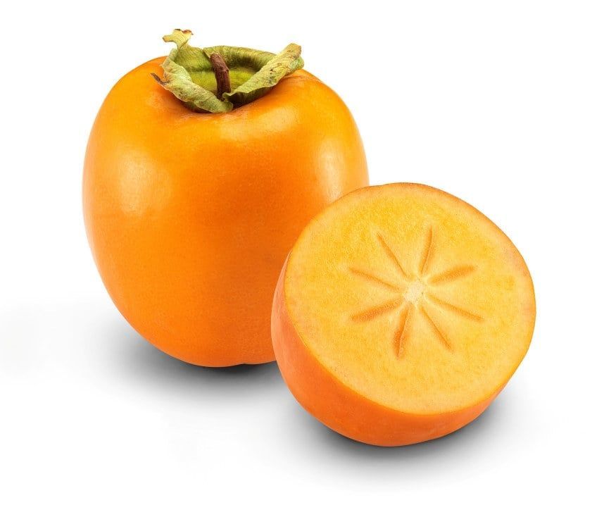 Kaki (persimon), én hel og én delt i to som viser gyllent fruktkjøtt med stjernemønster, plassert på hvit bakgrunn.