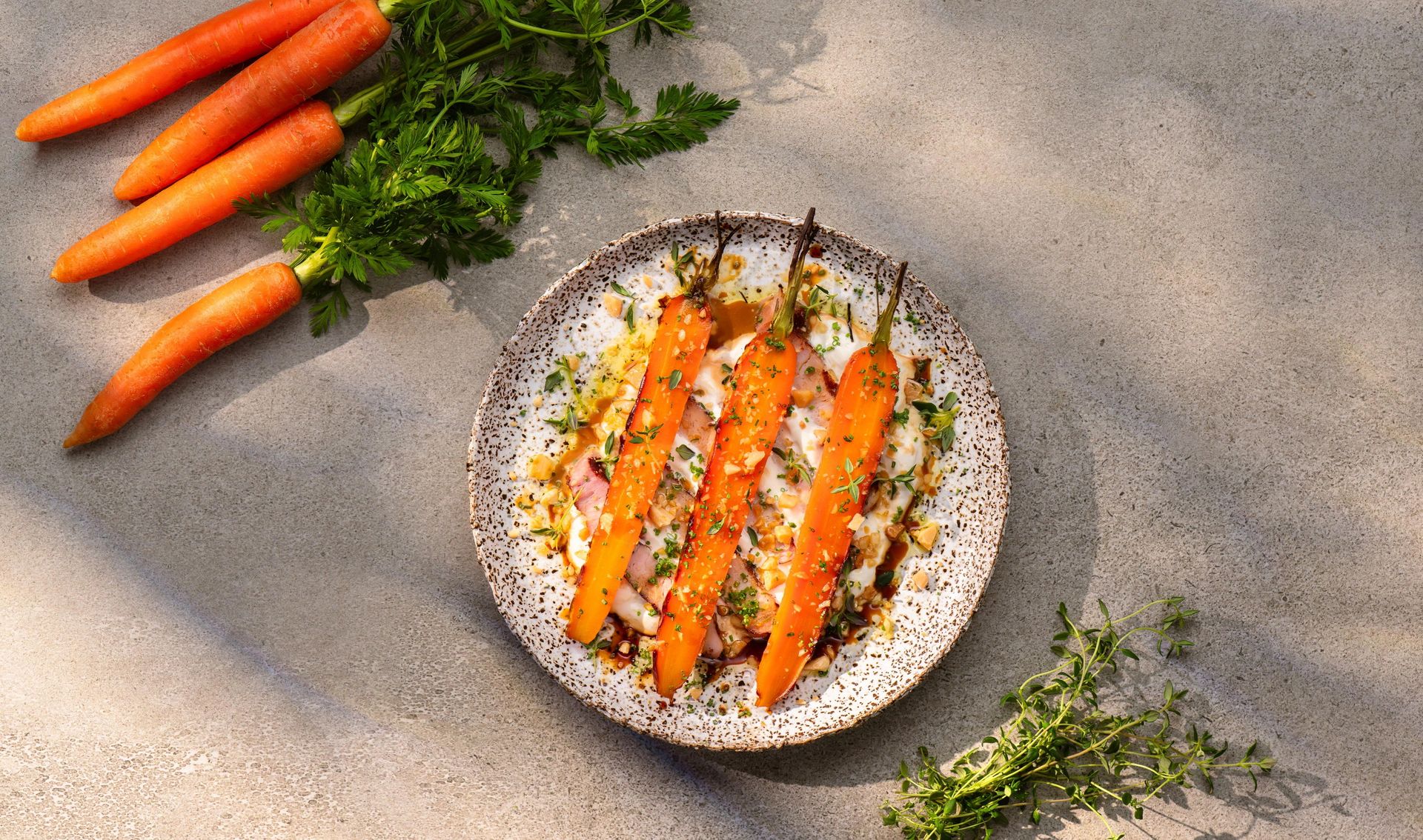 Grillede norske gulrøtter med yakitoriglaze servert på yoghurt og toppet med urter og hakkede mandler.