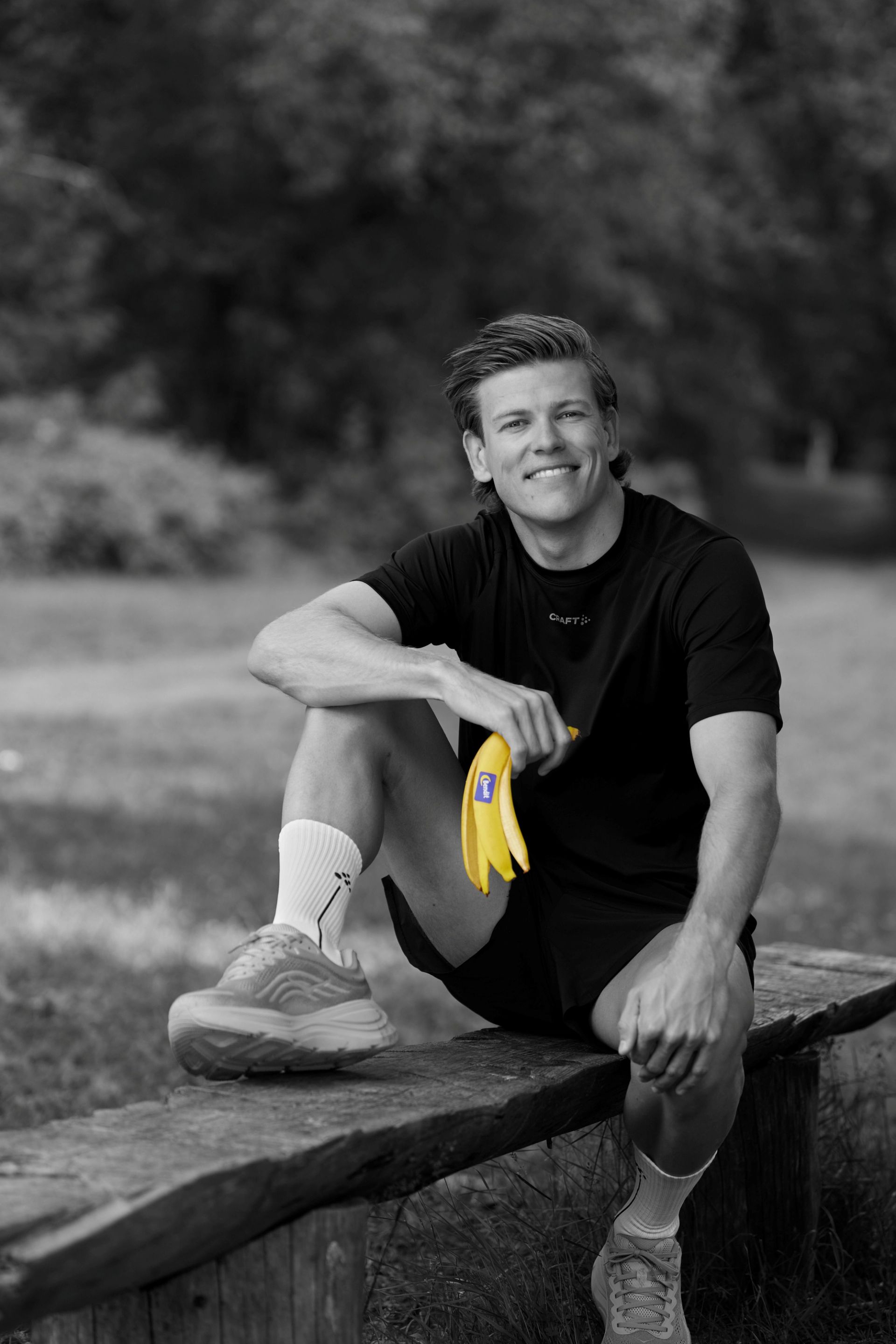 Klæbo på en benk med banan i hånden. 