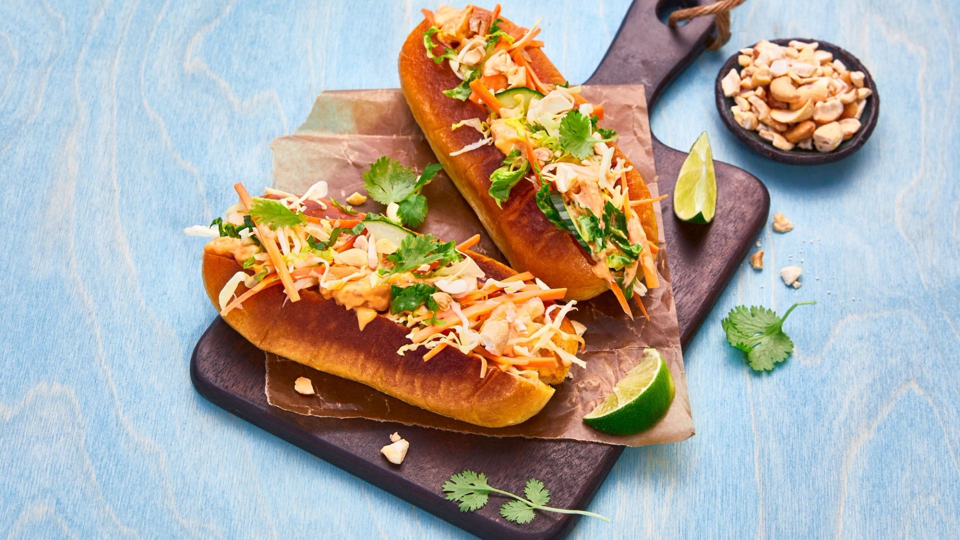 Banh mi med saftig kylling, sprø grønnsaker, koriander, lime og kremet dressing i gyllen baguette toppet med nøtter.