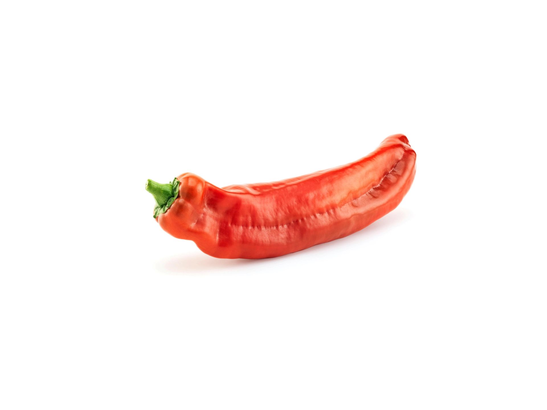 En hel rød søt paprika liggende på hvit bakgrunn.