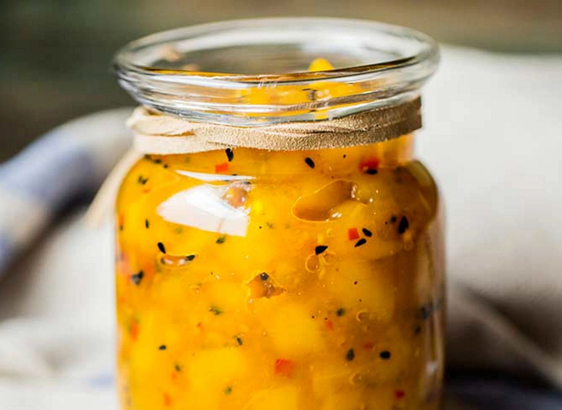 Hjemmelaget mangochutney med biter av mango og krydder servert i et glass.