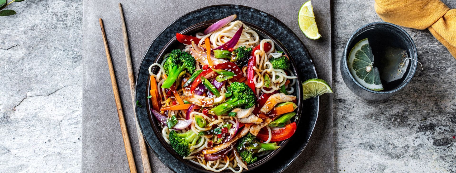 Spicy nudelwok med brokkoli og kyllingbryst servert i bolle med grønnsaker og nudler