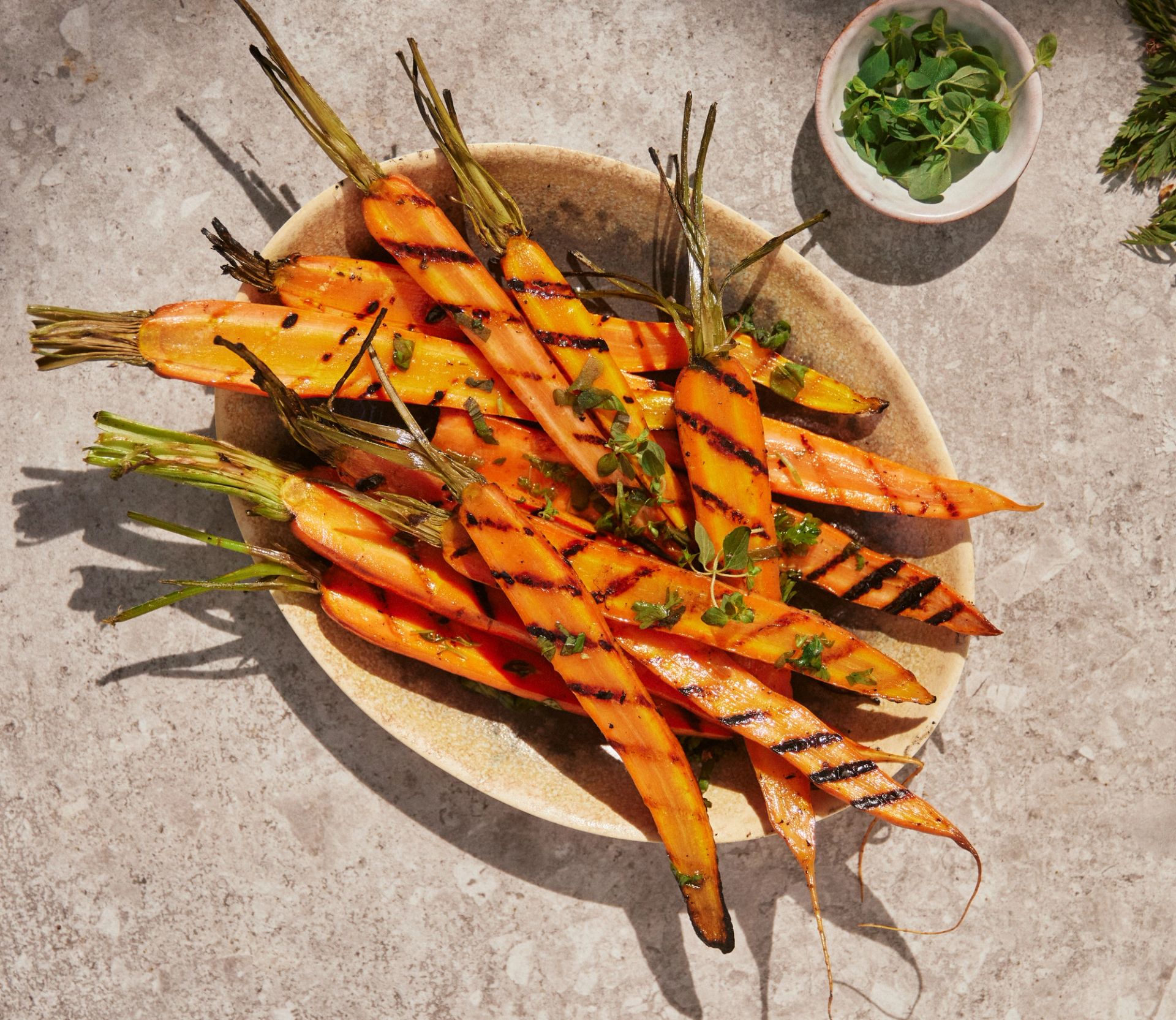 Grillede gulrøtter med urtevinaigrette og friske urter servert på rustikk tallerken