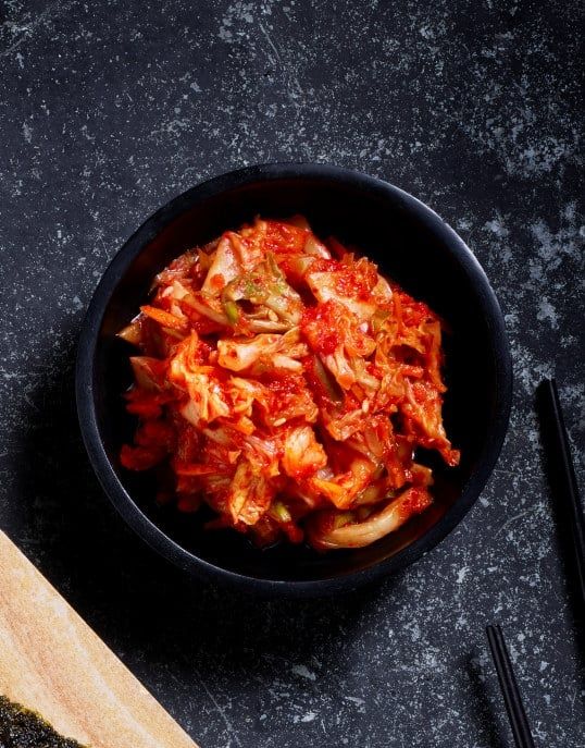 Koreansk kimchi av fermentert kål i sort serveringsskål