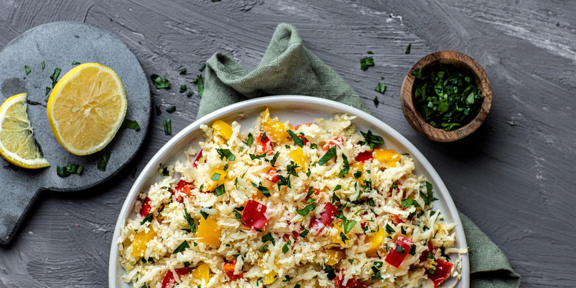 Blomkålris blandet med paprika, ingefær og persille, servert i skål med frisk grønn garnityr.